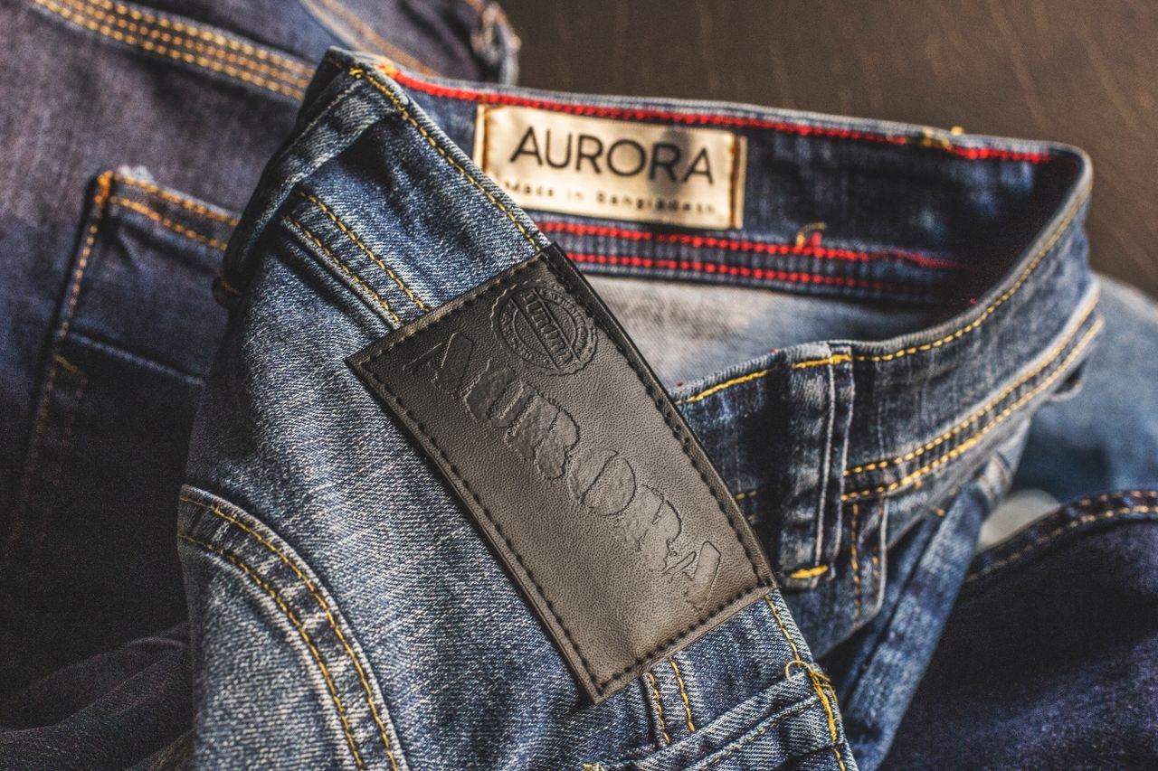journey-02 Close-up of blue denim jeans showcasing Aurora label, made in Bangladesh.