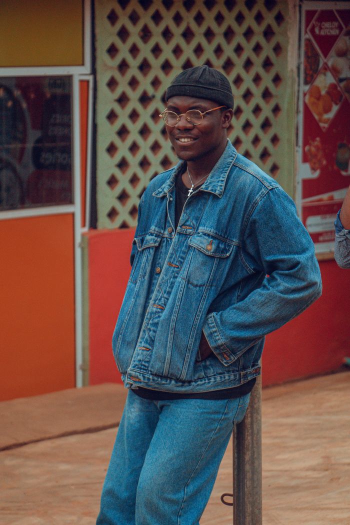 Mastering the First Impression: Your intriguing post title goes here Man in denim jacket and pants, smiling in an urban outdoor setting in Ife, Nigeria.