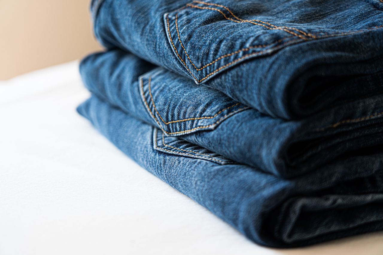 Crafting Captivating Headlines: Your awesome post title goes here Stack of neatly folded blue denim jeans highlighting stitching details.