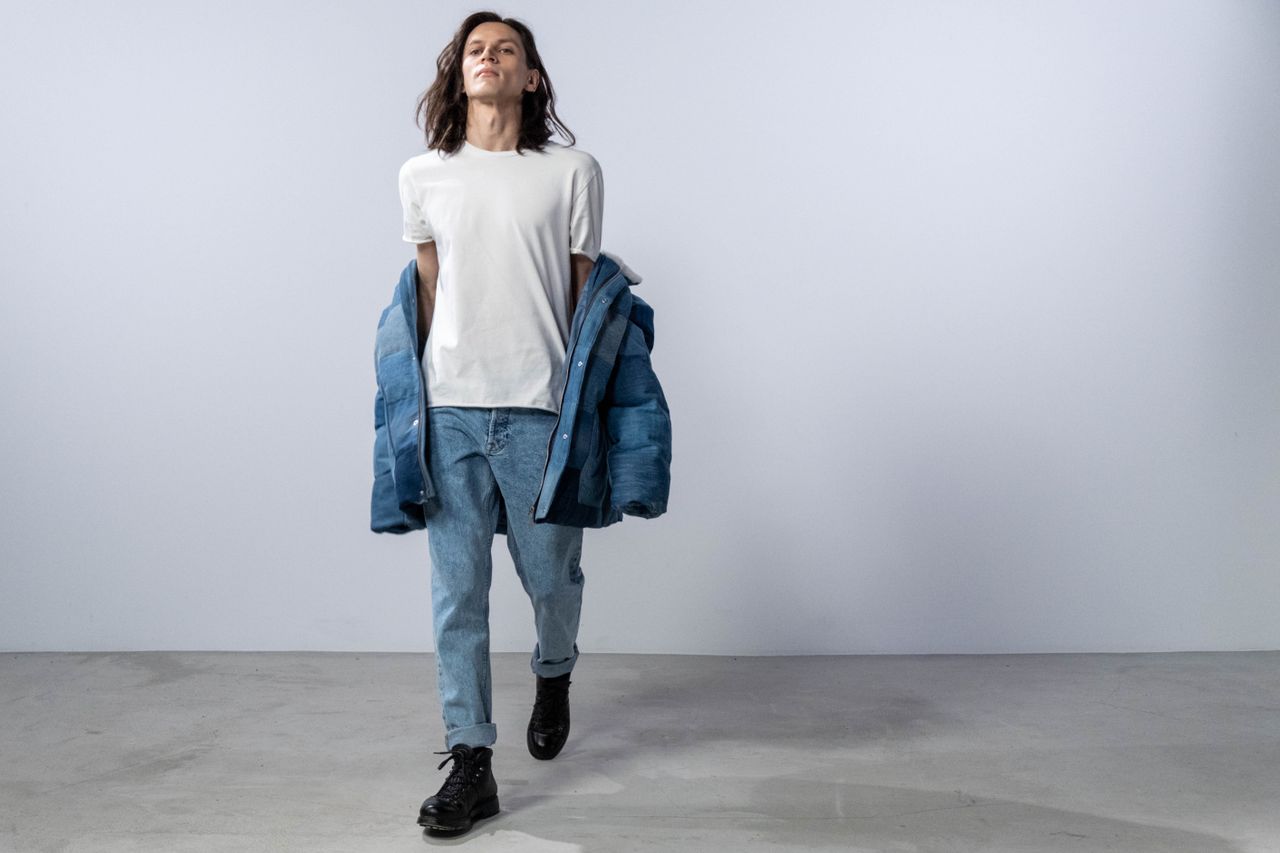 trusted-partner Fashionable male model wearing a jean jacket and jeans in a studio shoot with a white background.