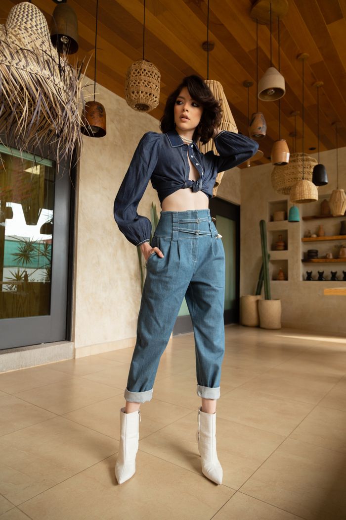 vision Fashionable woman indoors posing in chic denim and crop top outfit with stylish boots.